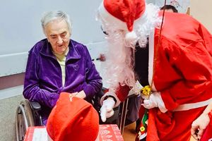 Mikołaj wręczający prezent seniorowi.