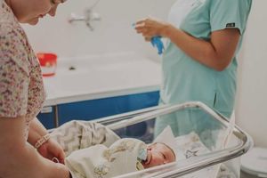 Noworodek w szpitalnym łóżeczku.