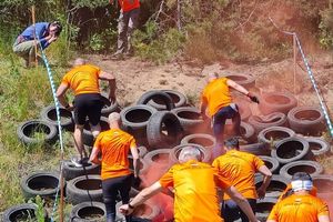 Biegacze pokonują przeszkodę z oponami.