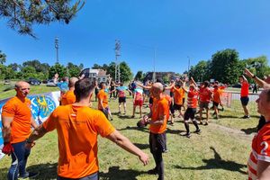 Zespół w pomarańczowych koszulkach, radość i świętowanie.