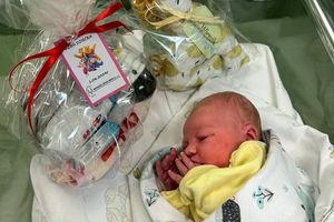 Noworodek w kocyku, prezent obok.