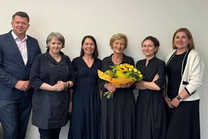 Grupa osób w strojach formalnych z bukietem kwiatów.